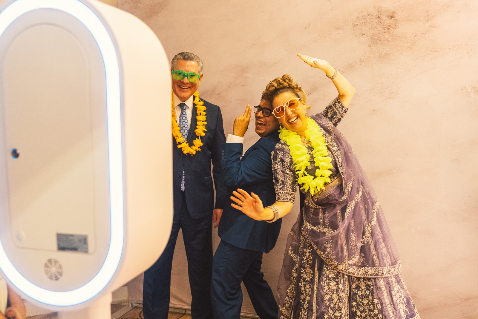 Guests in leis and party glasses dancing in front of a FlicBox photo booth